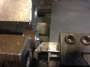 The 3/4 inch round stock is mounted in the three jaw chuck. It is faced and a 1/32 inch chamber is cut around the edge. The part is not faced all the way to the center, as it will be drilled out. This lessens the chance of damaging the cutting tool.