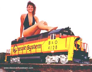 This was taken way back in 1976, That is Kim Kull, posing on a Koster's Miniature Railroad Supply GP-40 diesel on the trestle in Bill Koster's backyard. The locomotive is powered by 4 - .55hp motors and 5 golf cart batteries. From DiscoverLiveSteam.com, 2003.