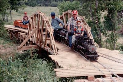 Dinky Creek Bridge on David Hannah's railroad and a happy day of completing the bridge except to tie in one piece of track. In the picture: David's son, Jack Lucks, George Maddox, and Willie. Believe me, that was a lot of work. Dinky Creek Bridge was modeled after a D&RG RR bridge in Colorado. Photo by Tom Stamey.